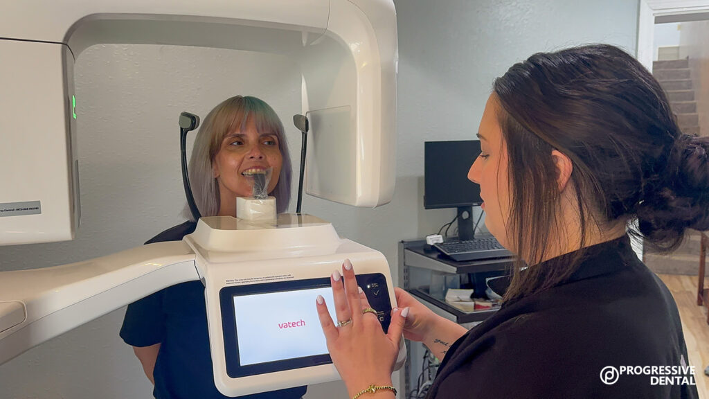A dental technician operates a panoramic X-ray machine as a patient stands ready, showcasing modern dental technology in Oklahoma City.